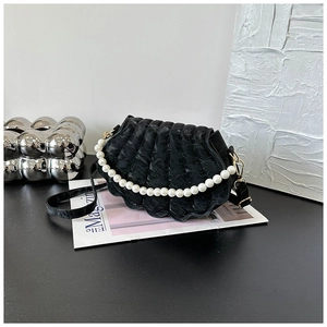 Close-up of black shell-shaped crossbody bag with luxury pearl handle and gold accents