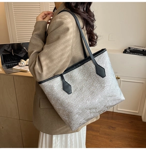 Detail of silver textured tote bag with black leather straps and woven pattern