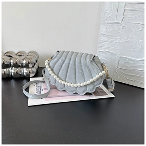 Detail view of light blue shell-shaped bag with pearl chain and leather strap