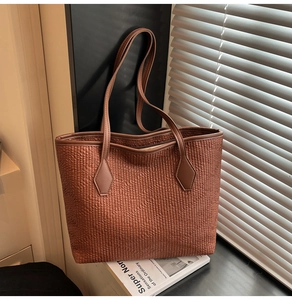 Detailed view of brown pleated faux leather texture and reinforced strap attachment of tote bag