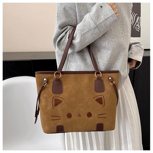 Close-up of a brown matte tote bag with cute cartoon cat face embroidery and long straps