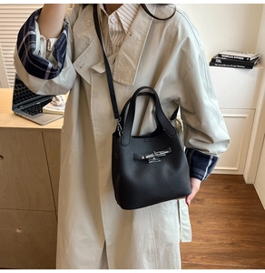 Détail du sac seau noir en cuir grainé avec fermoir pivotant argenté et bandoulière
