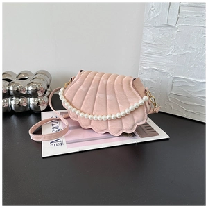 Detail of pink shell crossbody bag with pearl handle and golden metal clasp