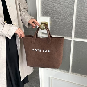 Sac fourre-tout en daim marron avec lettrage blanc suspendu à une poignée rétro