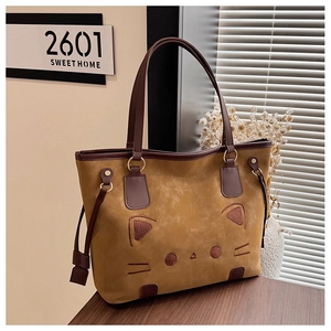 Detailed view of caramel suede tote bag with cute cat embroidery and leather handles