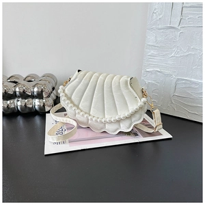 Detail of white shell-shaped handbag with pleated texture and decorative pearl handle