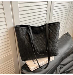 Close-up of the black tote bag with unique textured finish and leather handles