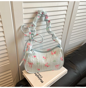 Detail of light blue floral handbag with pink roses and ruffled bubble gauze strap