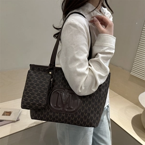Classic dark brown tote bag with M-pattern print and shoulder strap shown in a room
