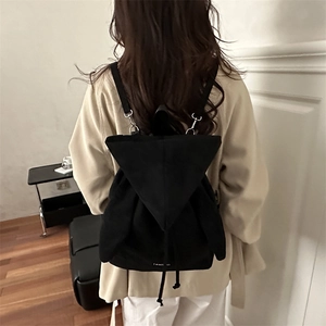 Minimalist black backpack with wing detail and drawstring closure shown on model