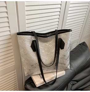 Close-up of silver tote bag featuring metallic embossed texture and black straps