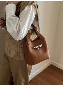 Détail du fermoir pivotant en métal argenté sur un sac seau en cuir grainé marron
