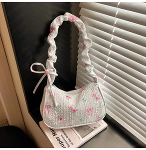 Detail of floral shoulder bag featuring ruffled handles and pink rose patterns
