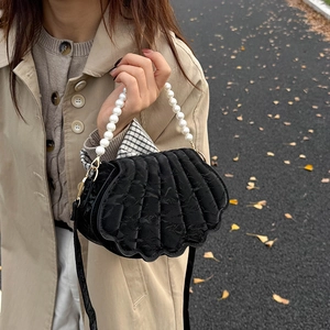 Fashionable black shell crossbody bag with pearl handle worn with a khaki autumn trench coat