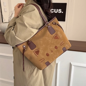 Brown suede tote bag with cute cat face design worn by model in minimalist setting