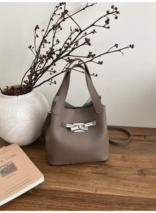 Détail du sac seau en cuir grainé avec fermoir rotatif argenté en forme de bambou