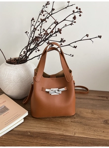 Détail du sac seau en cuir grainé marron foncé avec fermoir croisé en métal argenté