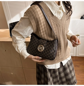 Retro-Umhängetasche mit M-Monogramm-Muster und Goldverschluss an einem Model getragen