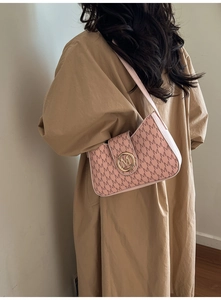 Detailansicht einer rosa Schultertasche mit Monogramm und goldener Logo-Schließe