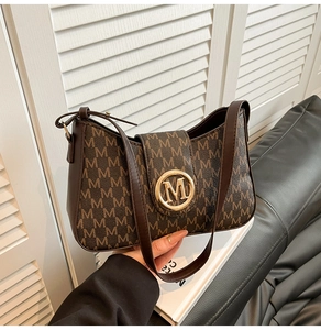 Detailansicht der braunen Vintage-Schultertasche mit Letter-Prints und Gold-M-Schnalle