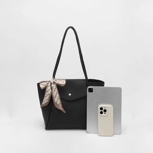 Detail of black pebbled tote bag showing interior capacity with tablet and silk scarf