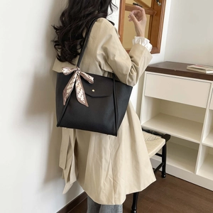 Detail of black pebbled leather tote bag with elegant silk scarf wrap on the handle
