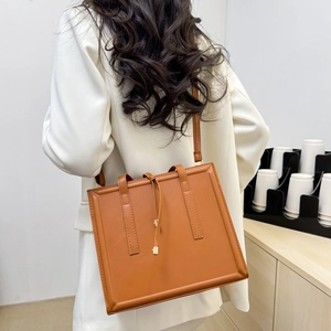 Sac bandoulière carré marron minimaliste avec fines lanières et détails dorés