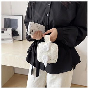 Detailed shot of white star pattern makeup bag with plush angel wings and metal zipper