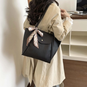 Close-up of black pebbled leather tote bag featuring a decorative H-pattern silk scarf