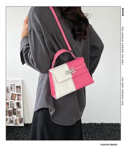 Detail view of pink and white color-block crossbody bag showing scale on model with strap