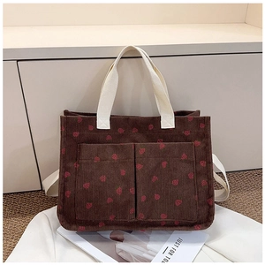Detail of brown corduroy tote bag with red strawberry print and double front pockets