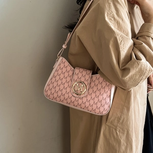 Rosa Schultertasche mit M-Buchstaben-Print und goldenem Logo am Model im Trenchcoat