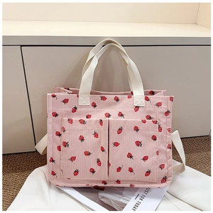 Detailed close-up of pink corduroy tote bag with red strawberry pattern and white handles