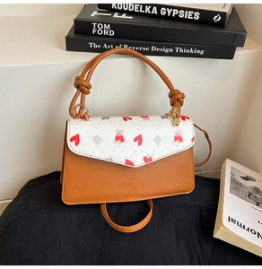 Detail of printed crossbody bag with red bear patterns and knotted handle design