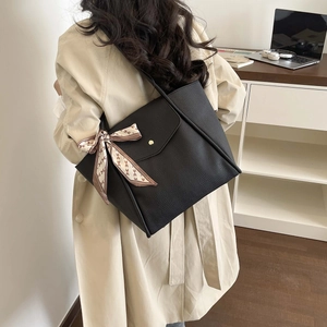 Black large capacity leather tote bag with silk scarf decoration worn by a model
