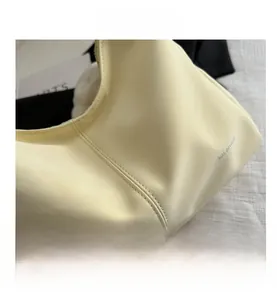 Close-up of beige lychee texture leather handbag with precise double stitching details