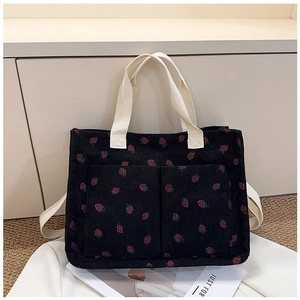 Detail of strawberry print corduroy tote bag with front pockets and sturdy handles