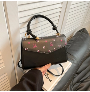 Detail of black stylish handbag with pink floral print and unique knotted handle design