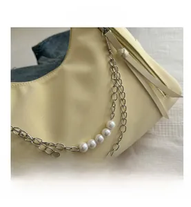 Detail of light yellow textured handbag with pearl chain and long leather zipper pull