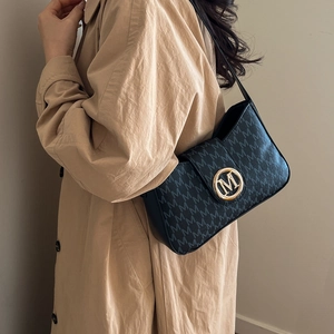 Schwarze Schultertasche mit M-Muster und Gold-Schnalle kombiniert mit Trenchcoat