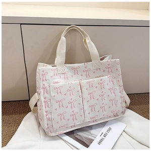Close-up of pink bow and heart print on corduroy tote bag with front pocket details