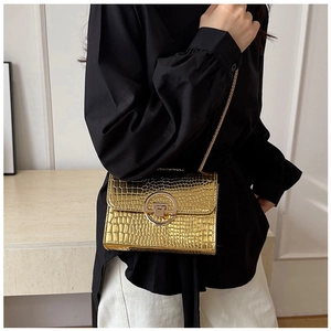Detail of gold faux crocodile crossbody bag with metal ring lock and chain strap
