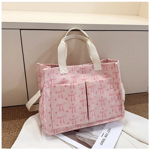 Detailed macro view of pink corduroy tote bag with bow patterns and cream ribbon handles