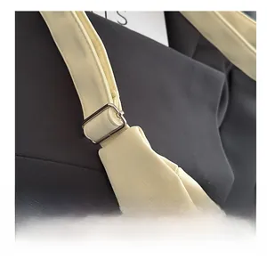 Detail of adjustable silver buckle on cream leather shoulder strap of a minimalist tote
