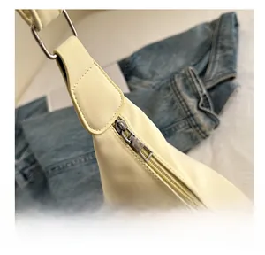 Close-up of smooth silver zipper and metal buckle on beige leather shoulder bag