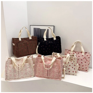 Detail view of corduroy tote bags with strawberry and bow patterns in multiple colors