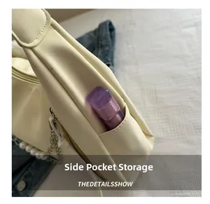 Detail view of the side storage pocket on an ivory PU leather bag with pearl chain decoration