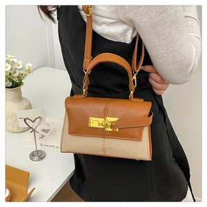 Détail du sac trapèze bicolore avec fermoir rotatif doré et texture en tissu tissé