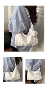 Detail of white leather hobo bag with plush cloud charm and adjustable wide strap