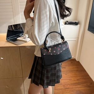Fashionable black leather handbag with floral print and adjustable shoulder strap
